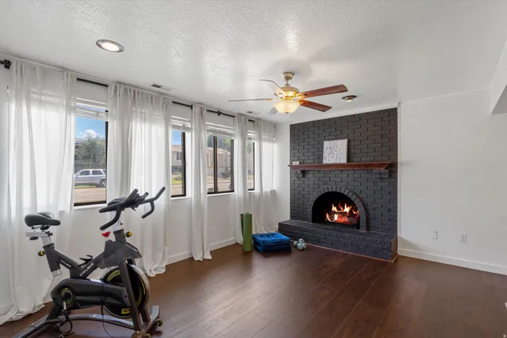 Recessed lighting, ceiling fan, wood-finish flooring, and a fireplace with a brick surround and wood mantel