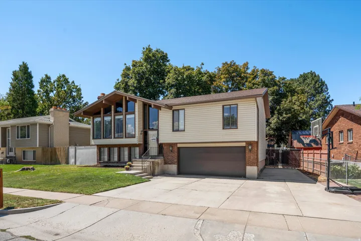 Split-level residence featuring a prominent front lawn, a two-car garage, and an extended driveway