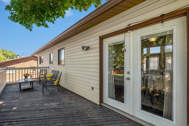 Expansive outdoor deck with wood railing, featuring double glass doors, and durable siding