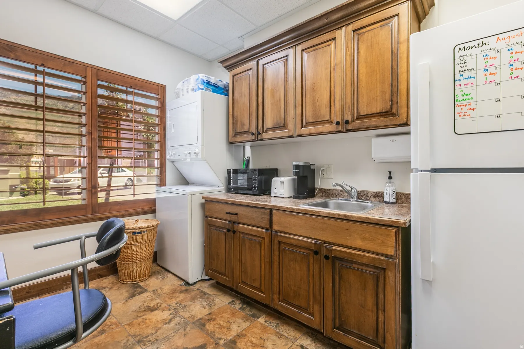 Wood-finish cabinetry with dark hardware, a stainless steel sink, and a laminate countertop