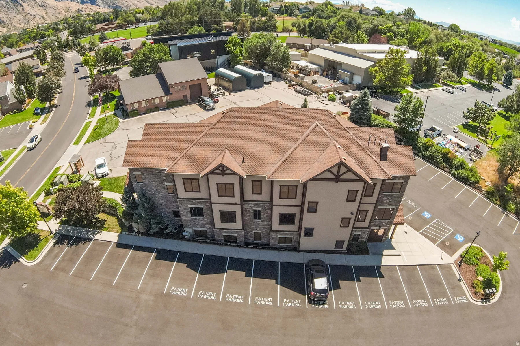 Multi-story commercial building featuring a pitched roof, stone and stucco exterior, and ample paved parking