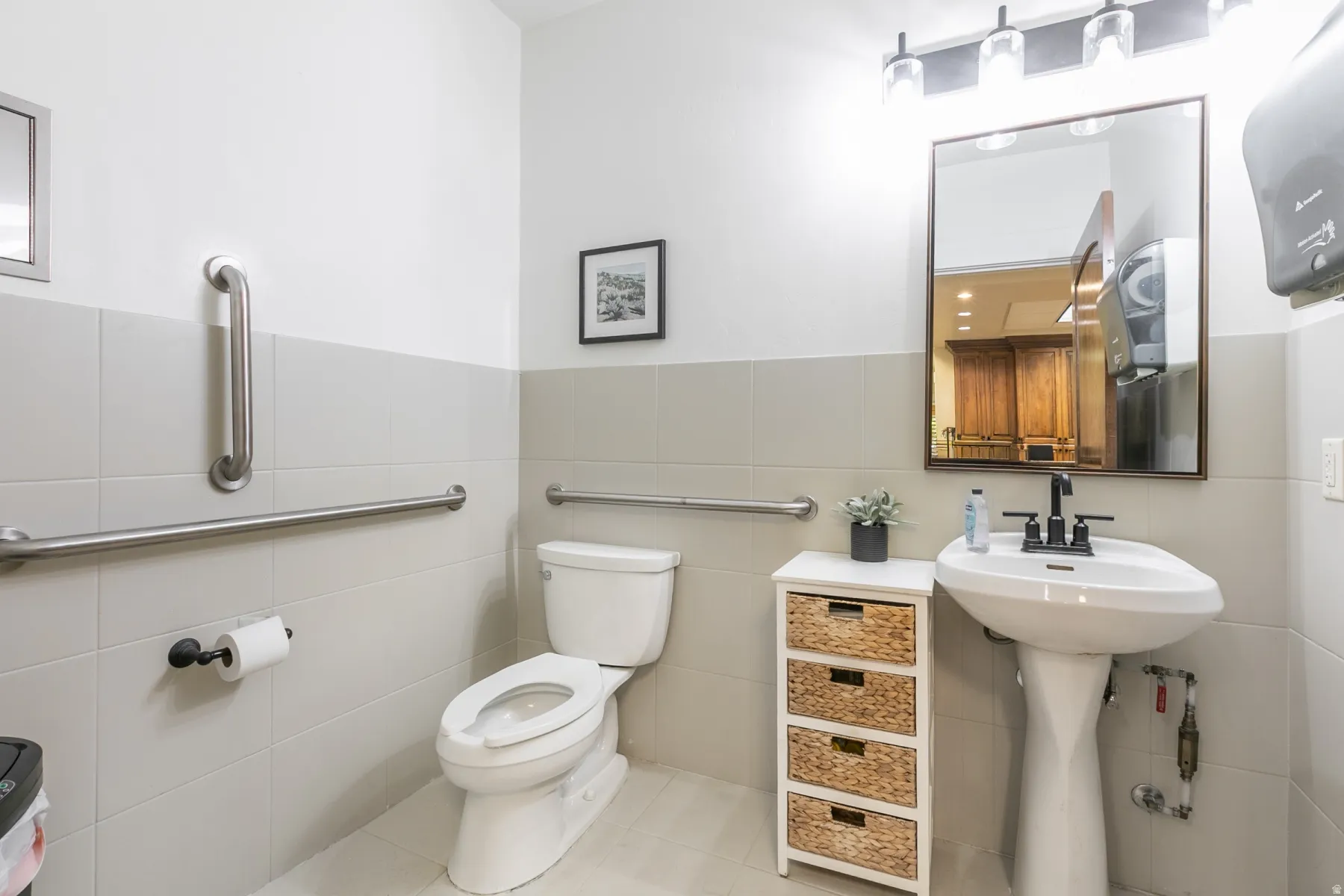 White pedestal sink with a matte black faucet, wall-mounted mirror, and vanity lighting fixture