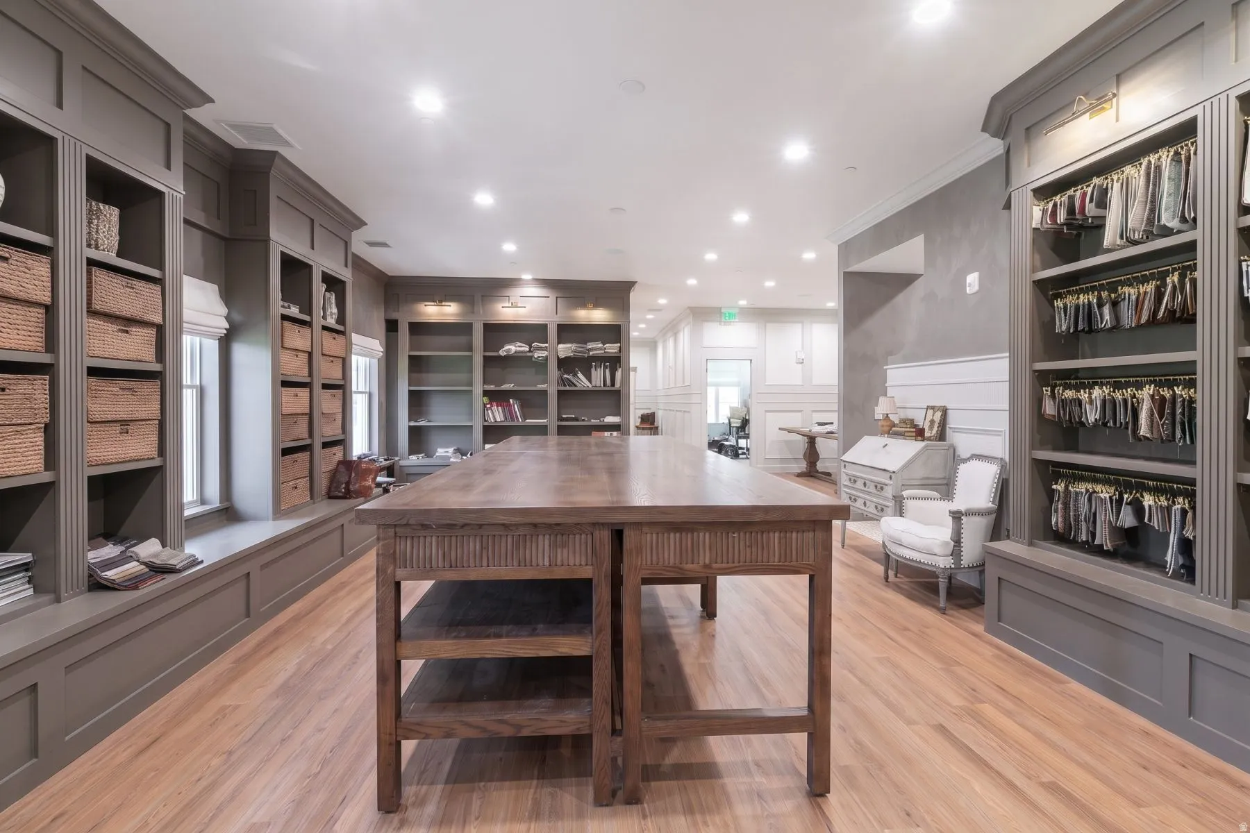 Built-in shelving with crown molding, wood-finish flooring, recessed lighting, and a substantial central wood table
