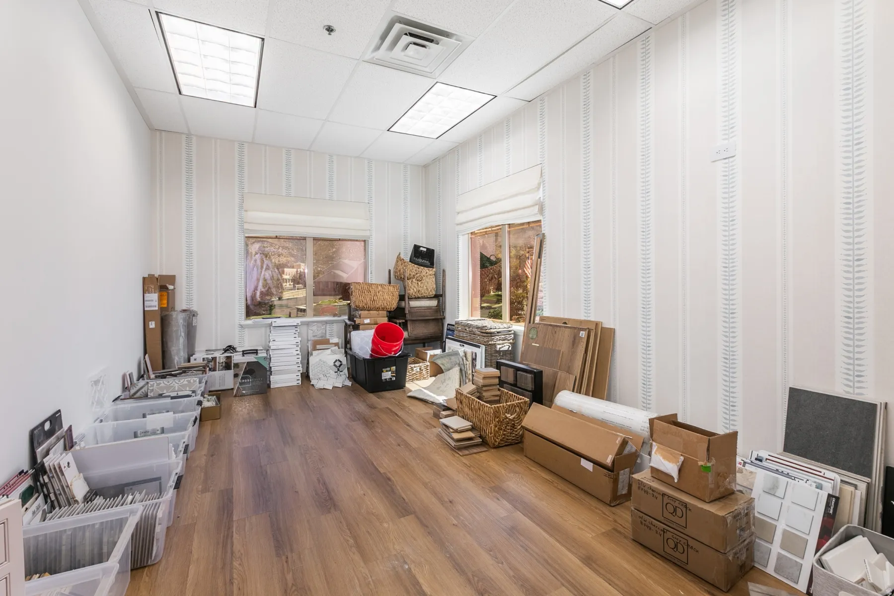 Recessed lighting, drop ceiling, wood-finish flooring, two windows with roman shades, and patterned accent wall