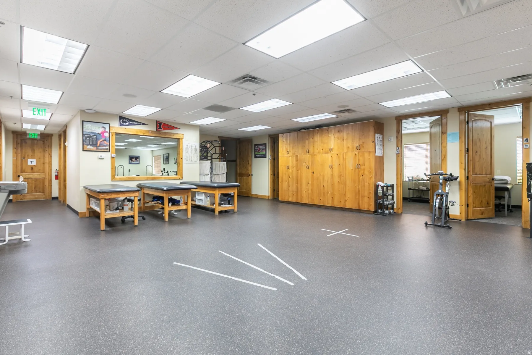 Spacious room featuring durable rubber-finish flooring, recessed lighting, and wood-paneled walls