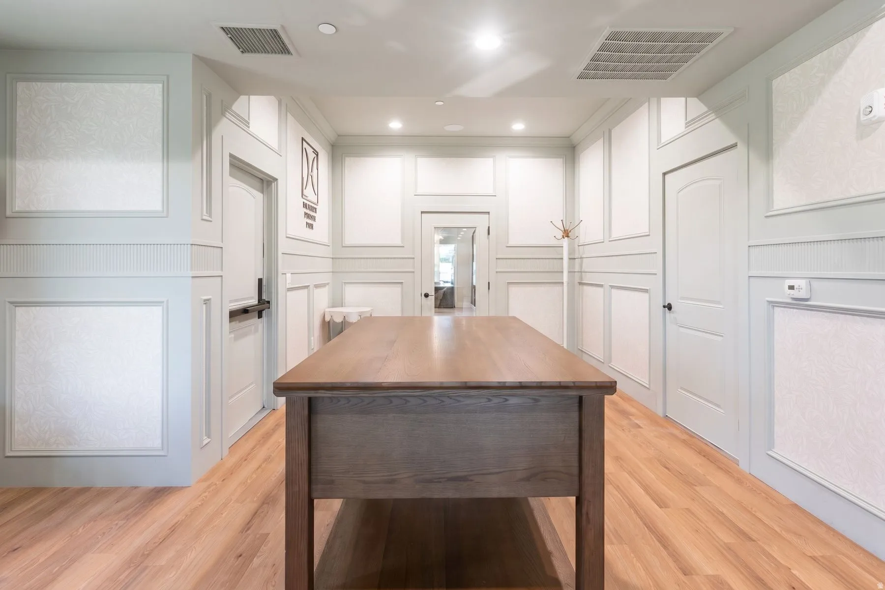 Wood-finish flooring, recessed lighting, decorative wainscoting, interior doors with arched panels, and a built-in table