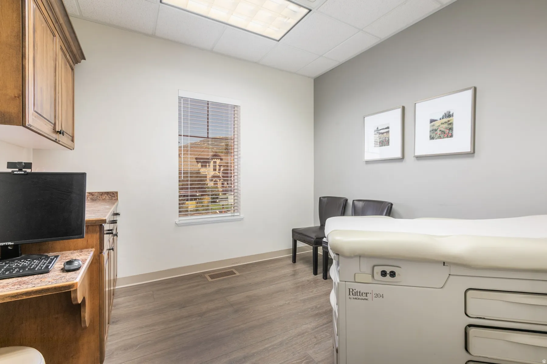Wood-finish flooring, built-in cabinetry with stone-finish countertops, and a window with horizontal blinds