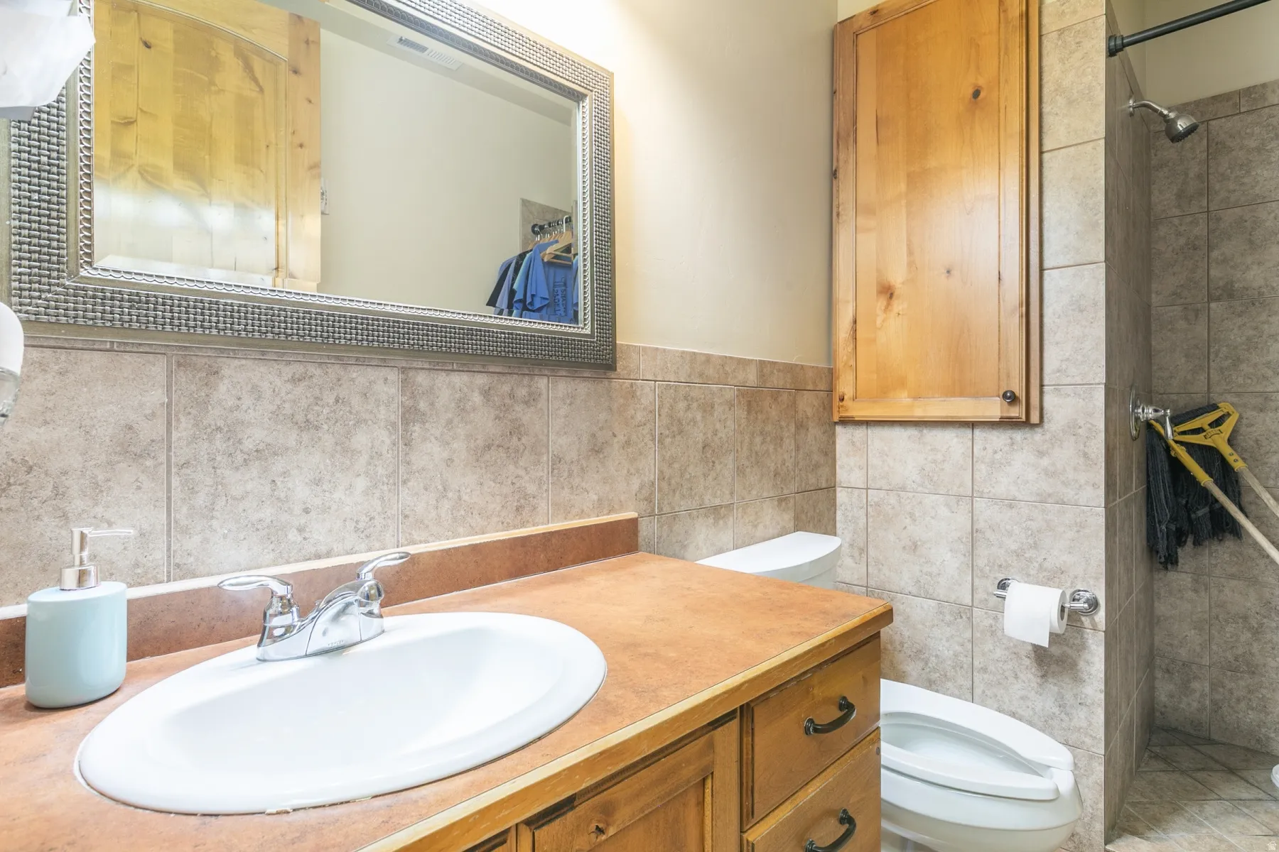 Vanity with an integrated sink, wood-finish cabinetry, and a textured mirror