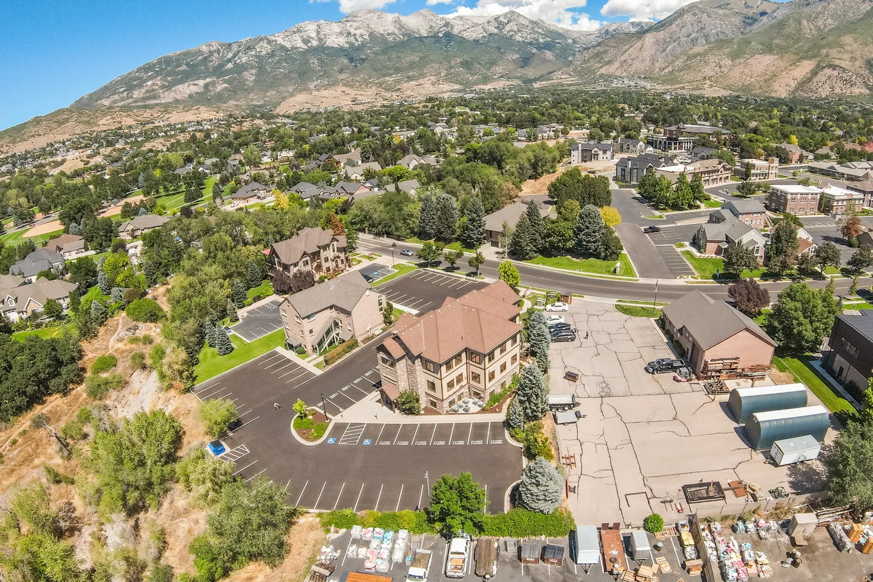 Expansive commercial property featuring multiple buildings, paved parking areas, and a mountainous backdrop