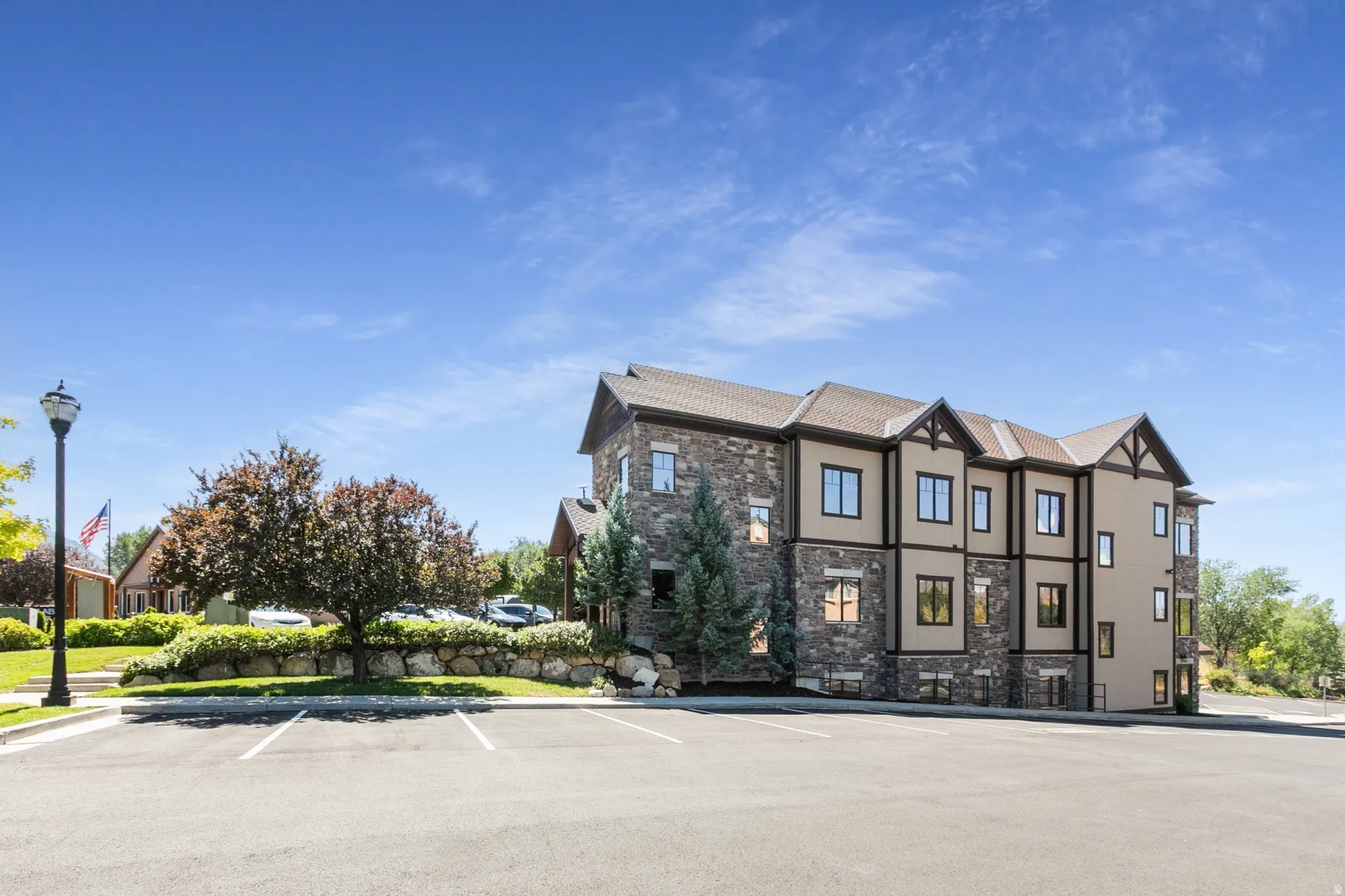 Stone and stucco exterior building with dark trim accents, multiple windows, and a shingle roof
