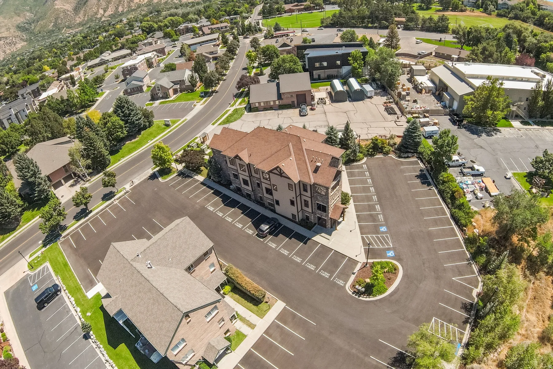Asphalt parking areas with marked spaces, mature landscaping, and surrounding commercial buildings