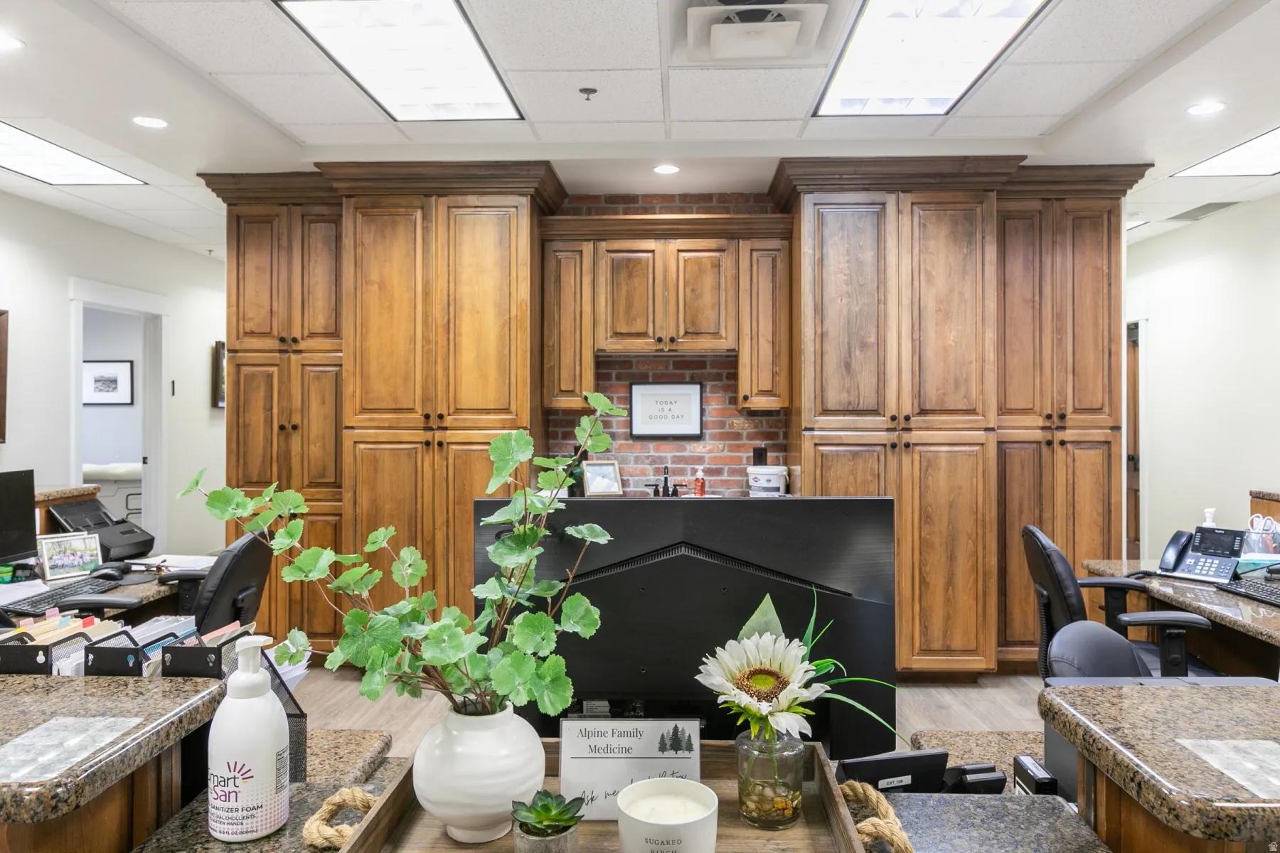 Extensive built-in wood cabinetry, brick-finish wall accent, and wood-finish flooring