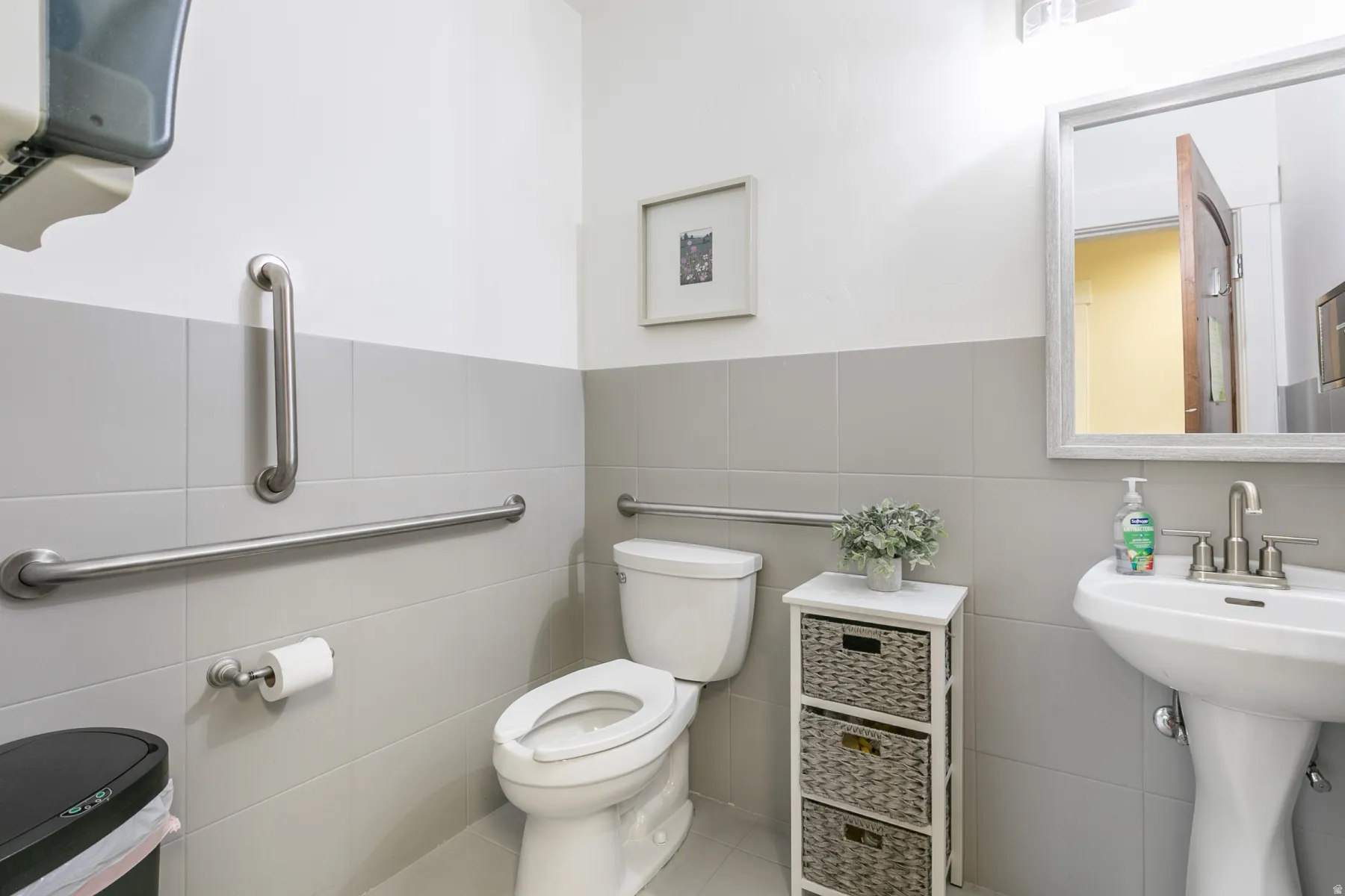 Bathroom featuring a white pedestal sink, toilet, and tiled walls