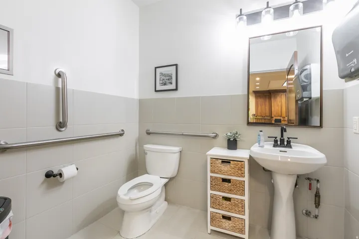 White pedestal sink with a matte black faucet, wall-mounted mirror, and vanity lighting fixture