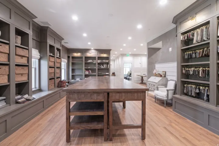 Built-in shelving with crown molding, wood-finish flooring, recessed lighting, and a substantial central wood table