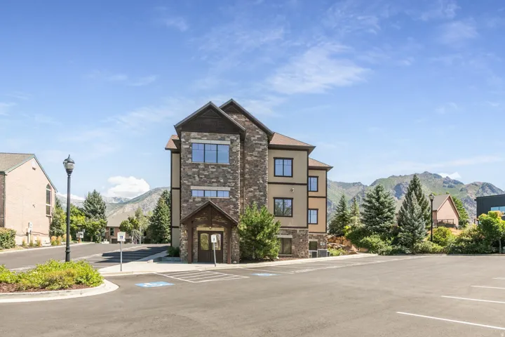 Multi-story building featuring stone and stucco exterior, multiple windows, and a prominent entrance