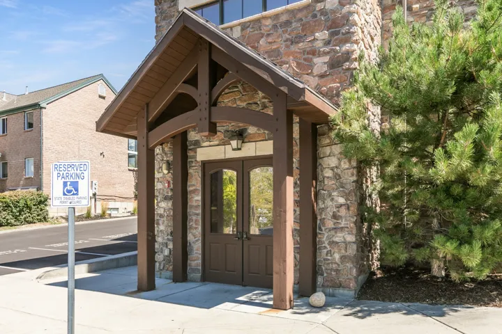 Stone facade with wood-beam entry canopy and double glass-paneled doors
