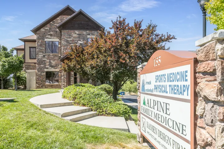 Stone veneer exterior with multiple windows, concrete steps, and a stone-clad sign