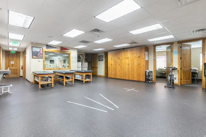 Spacious room featuring durable rubber-finish flooring, recessed lighting, and wood-paneled walls