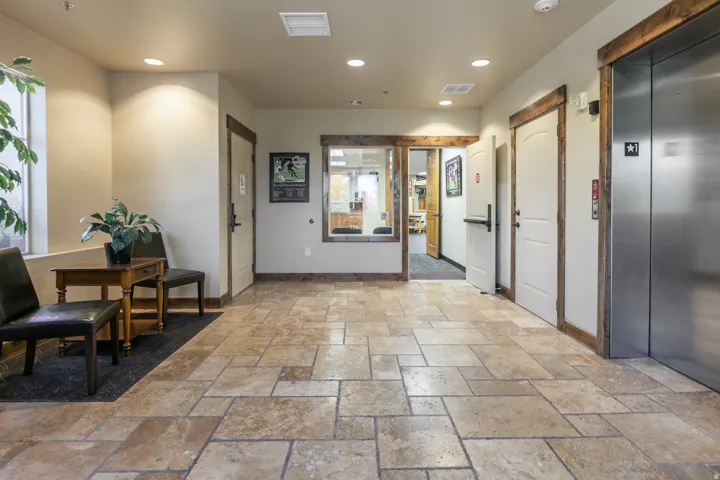 Tiled flooring throughout, recessed lighting, wood-trimmed doorways, and a stainless steel elevator