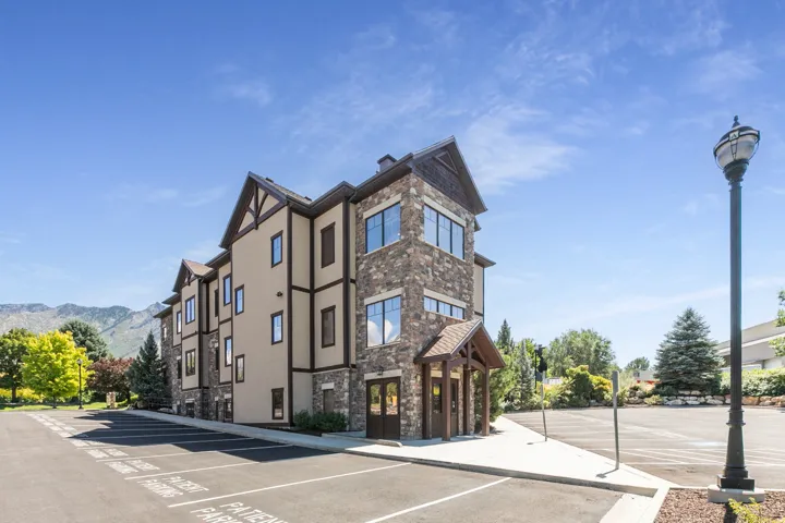 Three-story building featuring stone and stucco exterior, prominent gables, and multiple windows