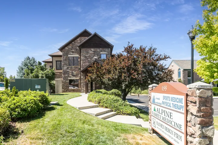 Stone and stucco exterior with dark-framed windows, a prominent gable, and a curved concrete walkway