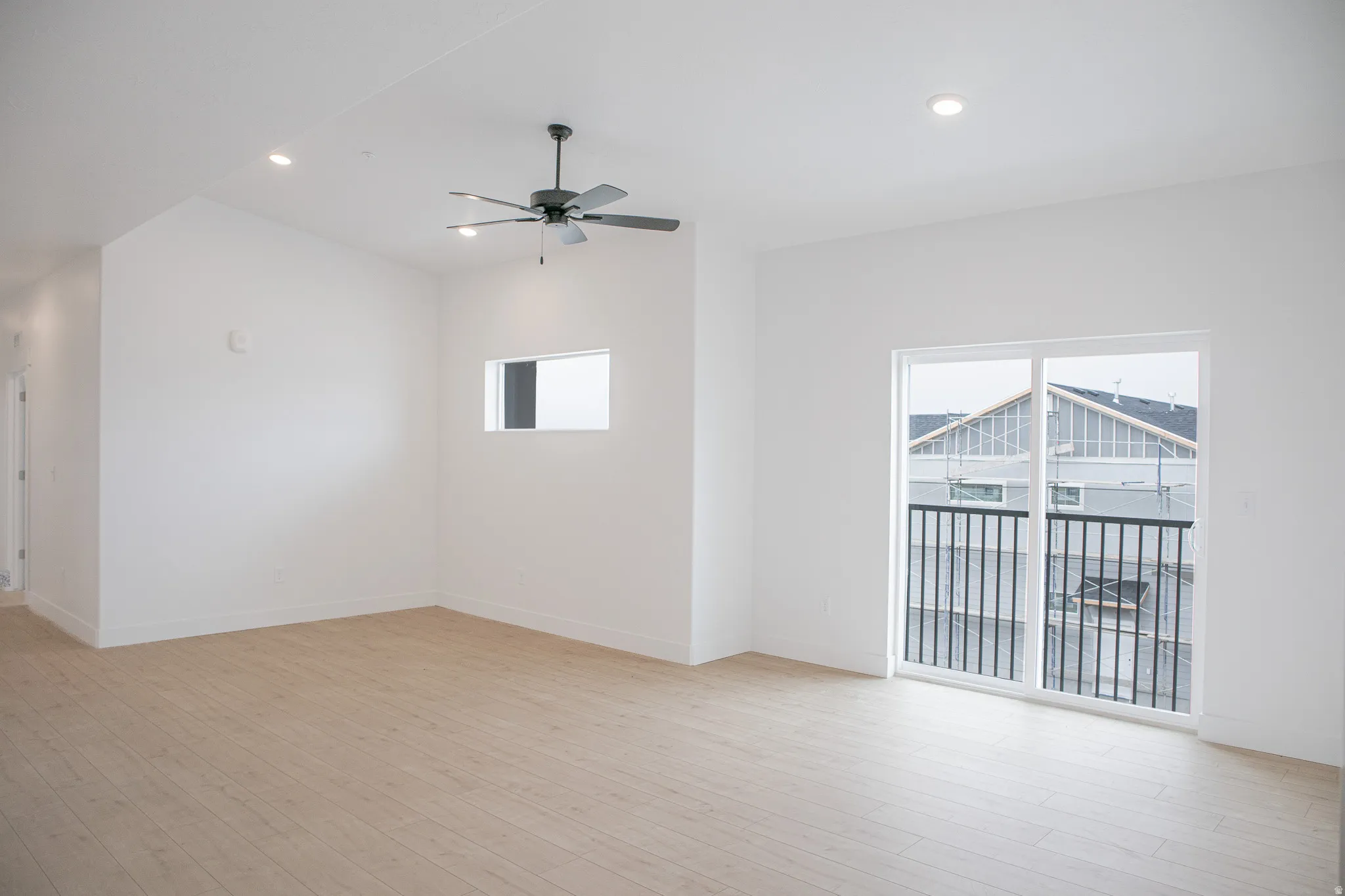 Family room with vaulted ceiling, ceiling fan and balcony.