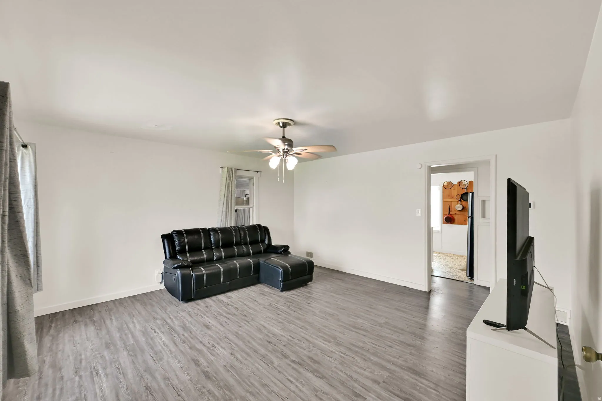 Spacious interior with neutral wall tones, wood-finish flooring, and a ceiling fan with integrated lighting