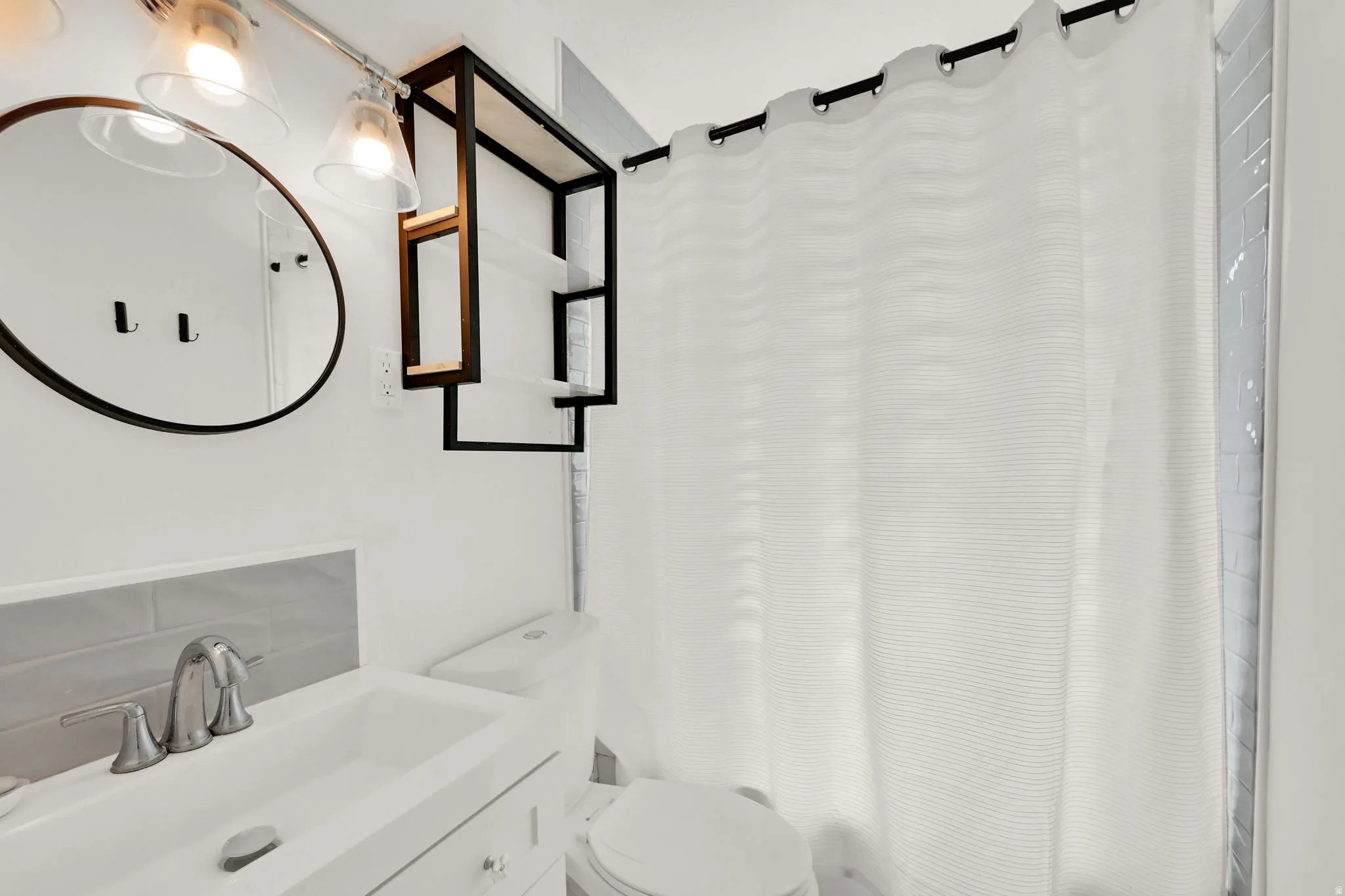 White vanity with under-sink storage, subway tile backsplash, and a round wall-mounted mirror