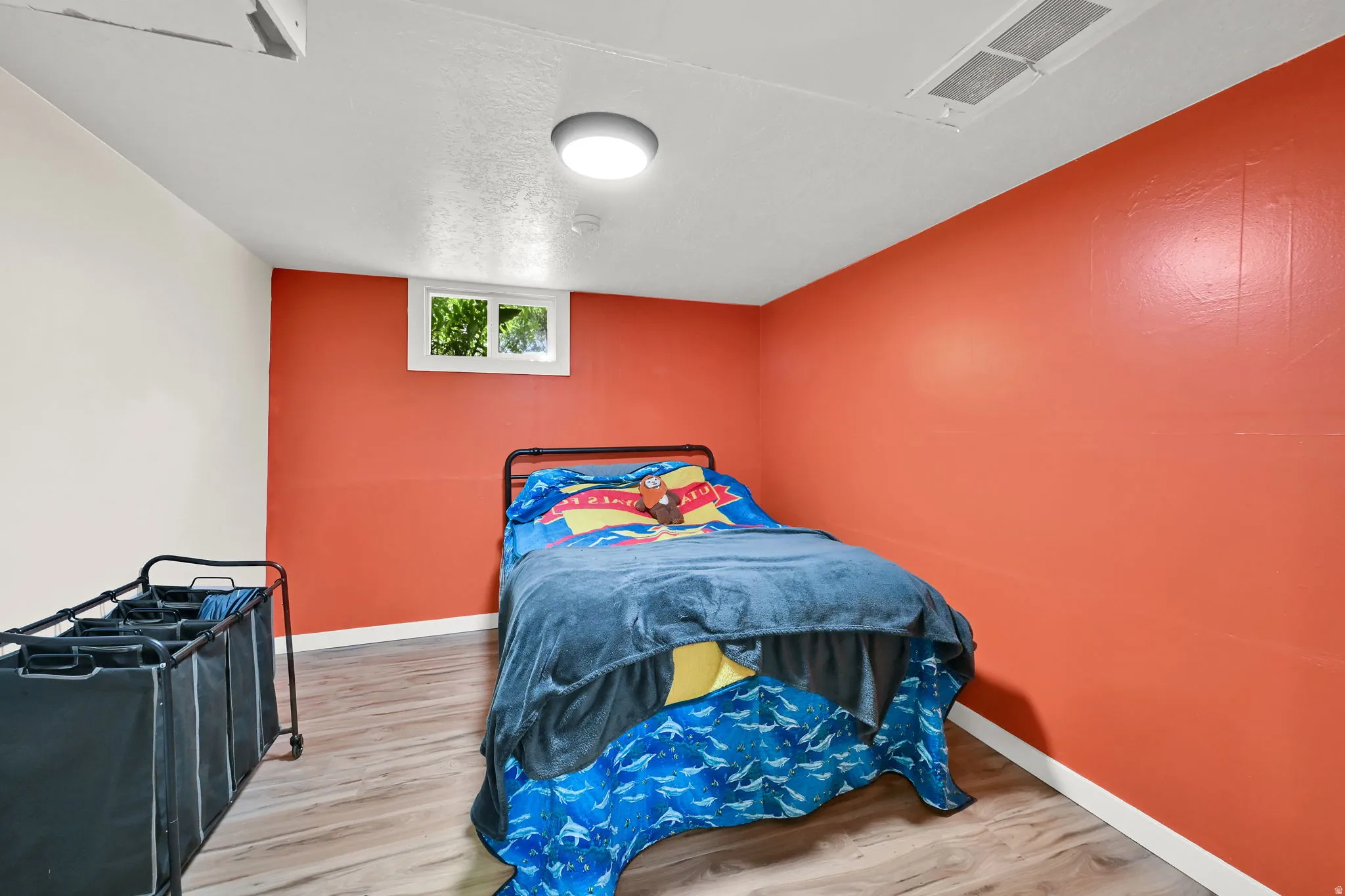 White framed window, wood-finish flooring, overhead flush mount light, red accent wall