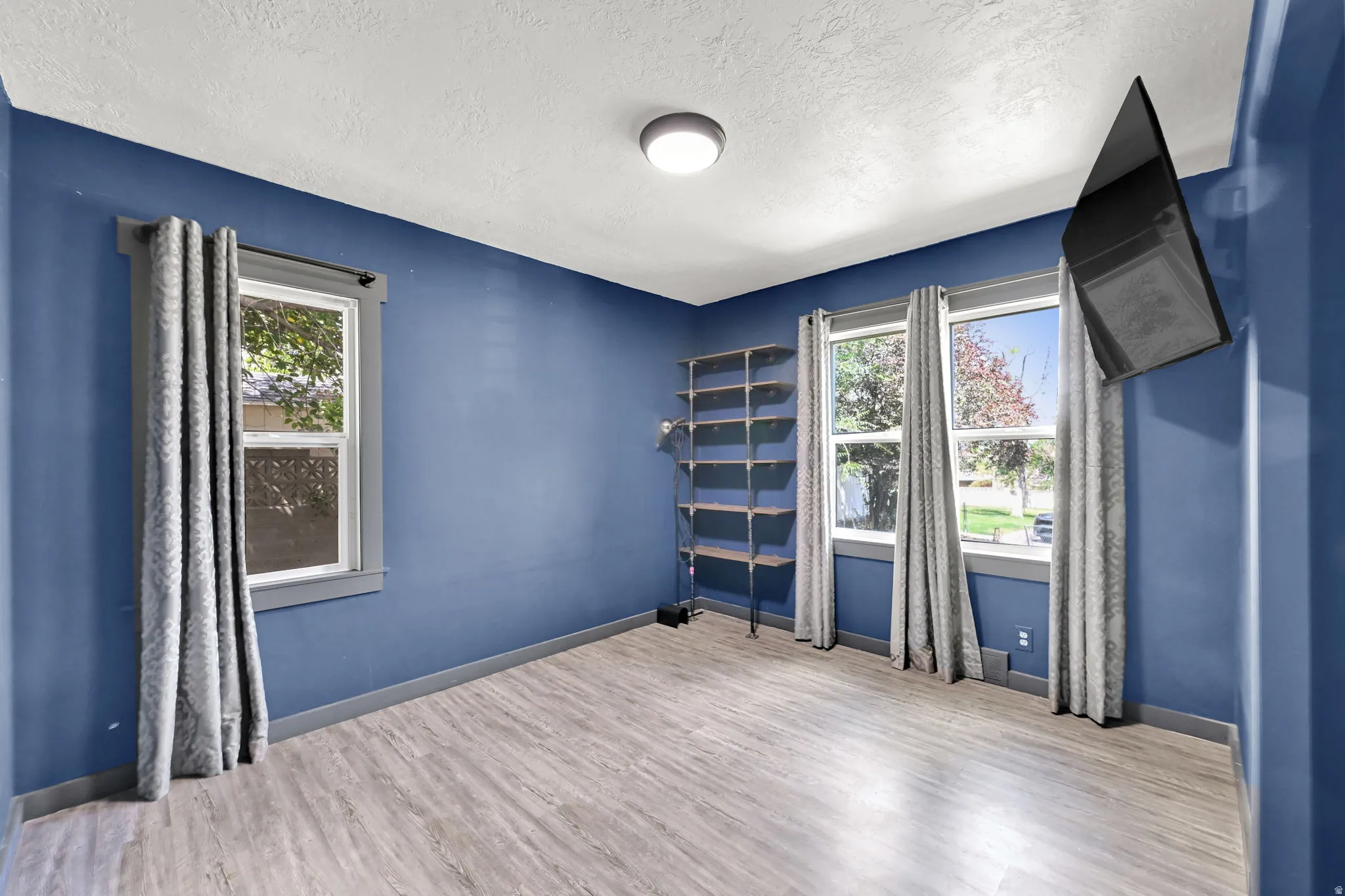 Wood-finish flooring, multiple windows, built-in shelving, and a ceiling-mounted light fixture