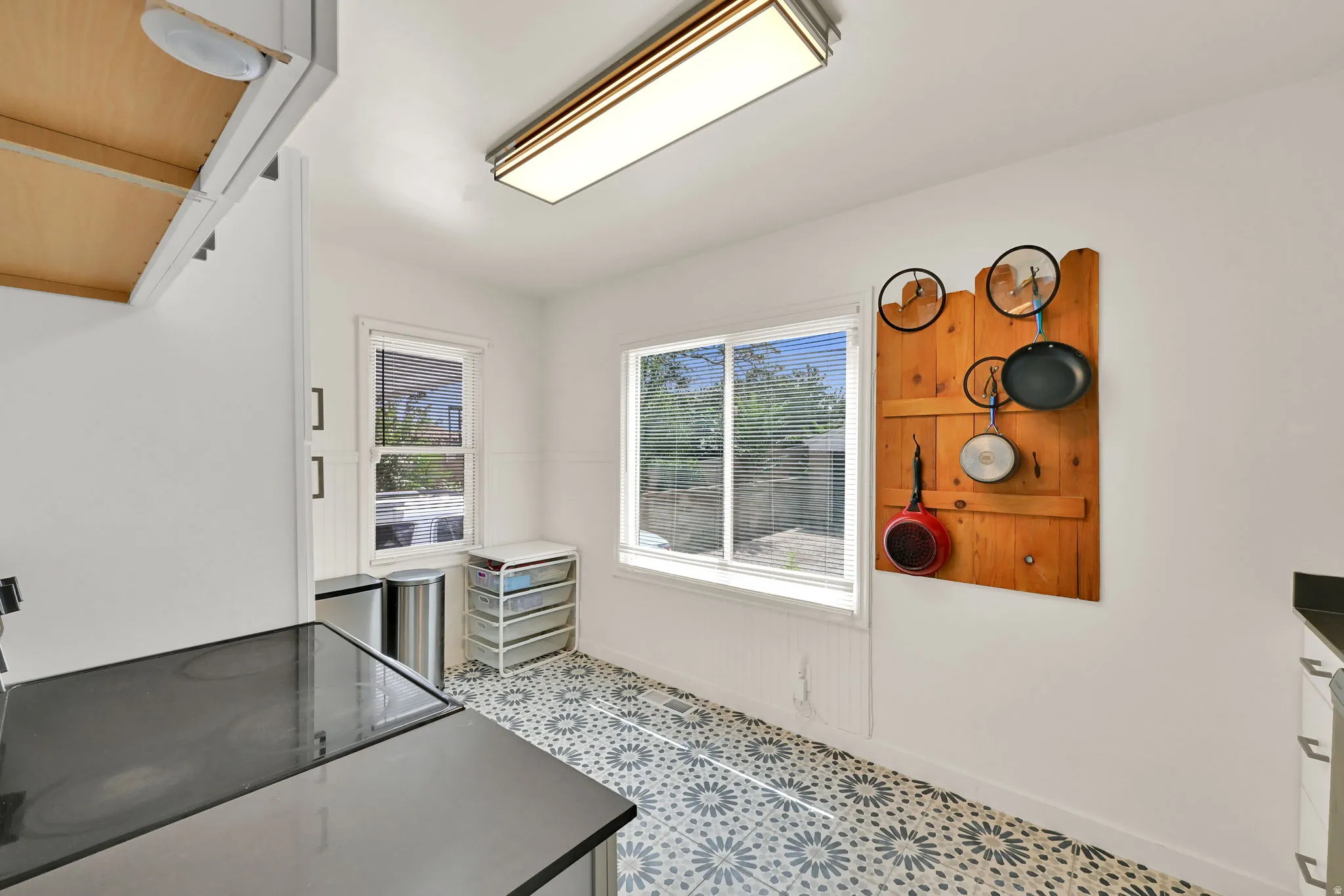 Patterned tile flooring, multiple windows providing natural light, white beadboard wainscoting, and a ceiling-mounted light fixture