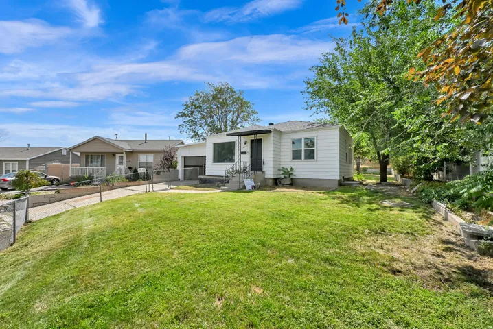 Single-story home featuring a white exterior, attached garage, and dark-trimmed windows