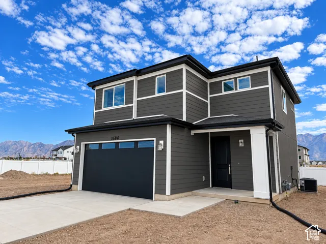Contemporary exterior with dark siding and white trim accents, featuring a two-car garage, multiple windows, and a covered entry