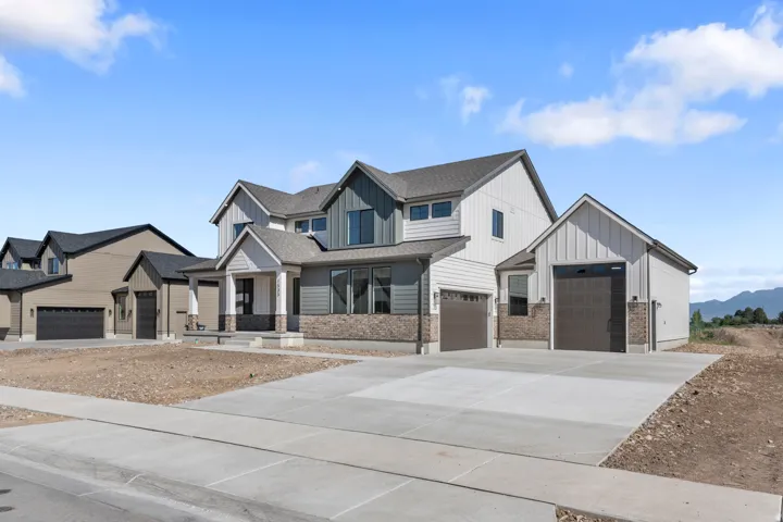 Two-story residence featuring a covered front entry and a multi-car driveway, complemented by a detached single-car garage and a brick accent facade