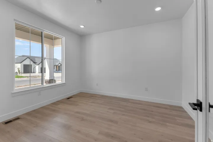 Recessed lighting, wood-finish flooring, white trim, and a large window