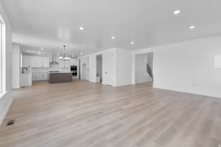 Spacious interior with light wood-finish flooring, recessed lighting, and a modern kitchen