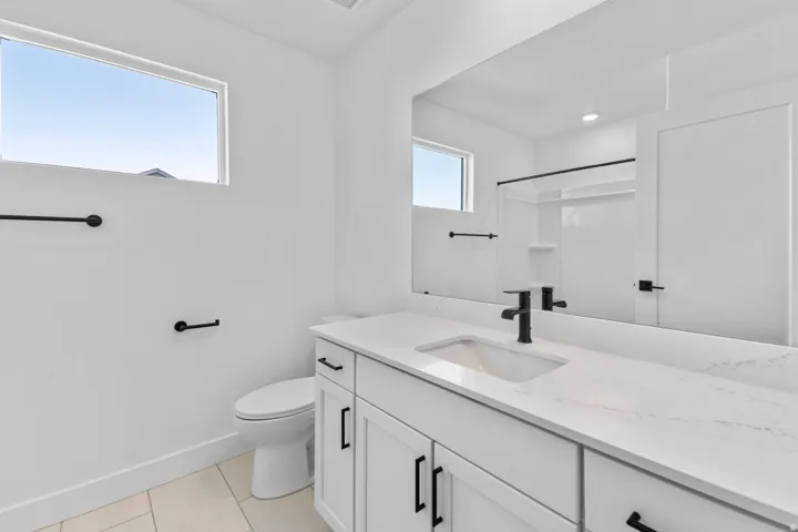 White vanity with a single basin sink, matte black faucet, and white countertop