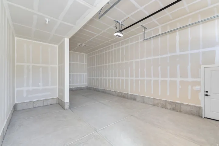 Concrete flooring, drywall ceiling, overhead lighting, interior access door, garage door track