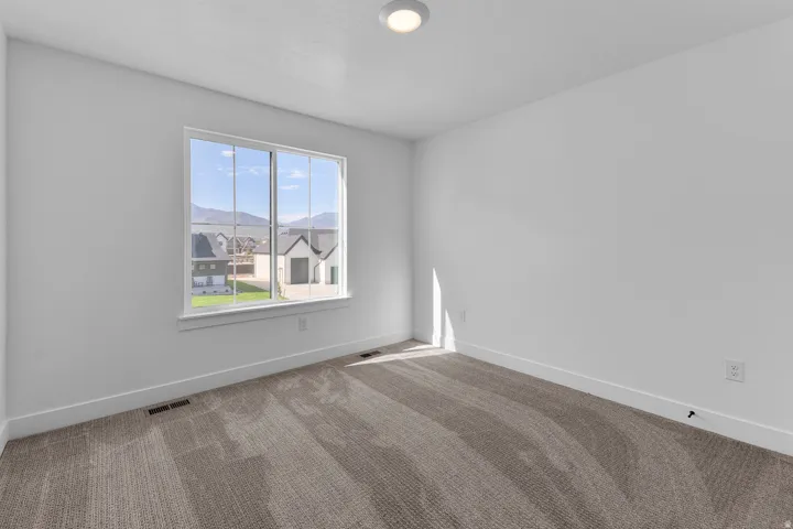 Neutral-toned carpeting, white walls, and a window with mountain scenery