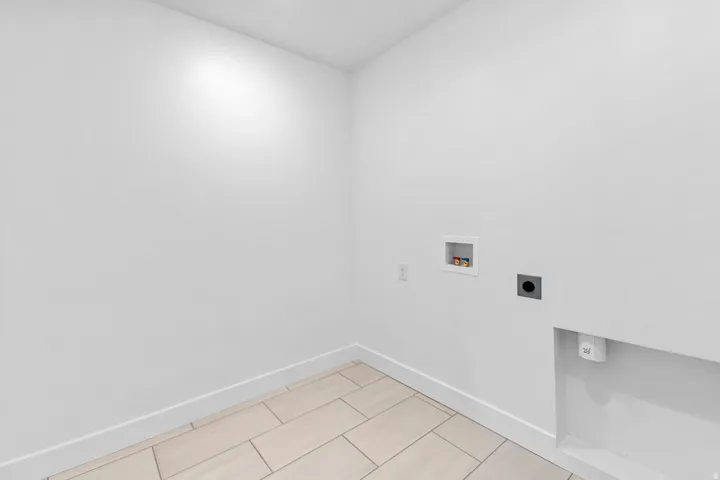 Recessed lighting, light-toned tile flooring, and clean white walls