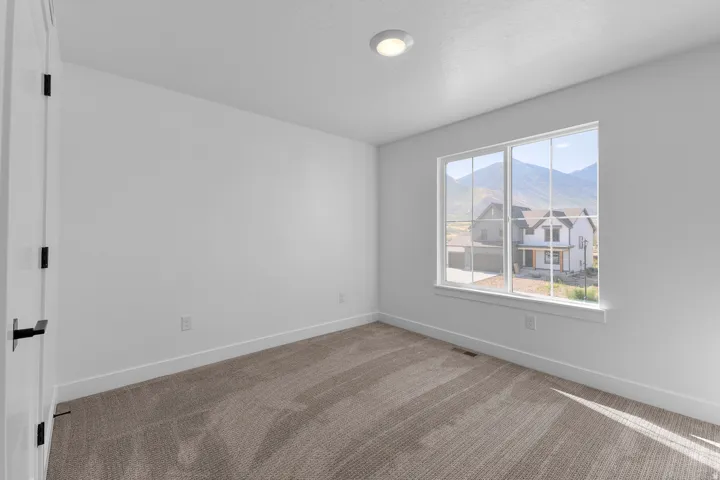 Carpeted room featuring a large window, flush mount ceiling lighting, and black door hardware