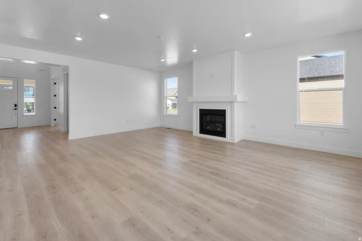 Spacious room with wood-finish flooring, a contemporary fireplace, recessed lighting, and multiple windows