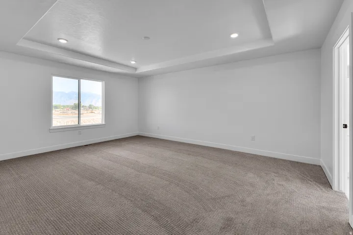 Recessed lighting, tray ceiling, wall-to-wall carpeting, white trim, and a window with mountain scenery