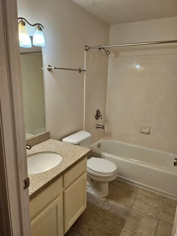 Vanity with granite-style countertop, integrated sink, and white cabinetry