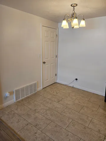 Recessed panel door, ceramic tile flooring, and a multi-arm chandelier