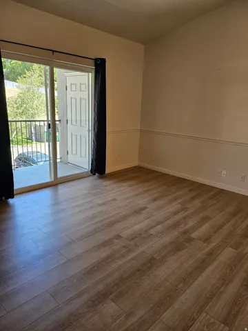 Wood-finish flooring throughout, with a sliding glass door leading to a private balcony