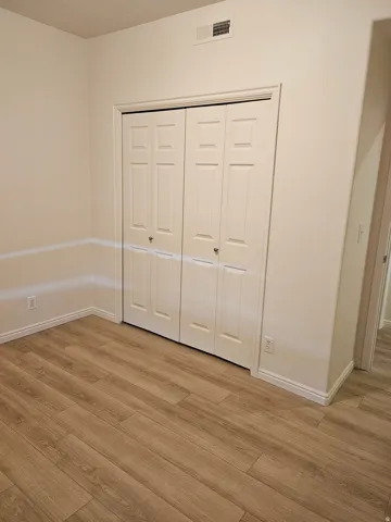 Warm wood-finish flooring with white baseboards and neutral wall tones