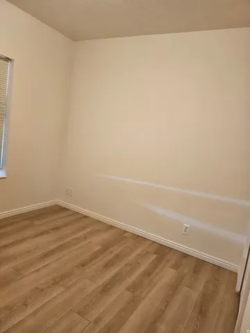 Wood-finish flooring with neutral wall tones and a window with blinds