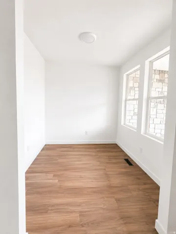 Recessed ceiling lighting, wood-finish flooring, multiple windows, and white baseboards